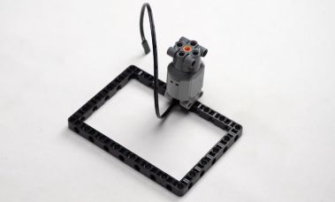 Connect the motor to the block, demonstrating the crucial setup step for the goal-scoring robot, perfect for hands-on learning in robotics for kids.