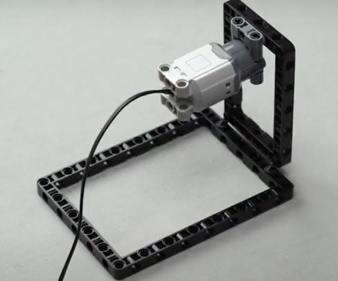 The Technic DC motor is then attached on the frame of the spin wheel robot by the Technic pin connector with the help of the two frictionless Technic pegs.This finishes 25% of the build of our spin wheel robot, a beginner robotic project.