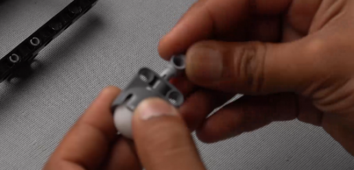 Attaching the caster wheel to the pin connector using the block joiner, preparing the Follow Me Home robot for enhanced movement and object detection.