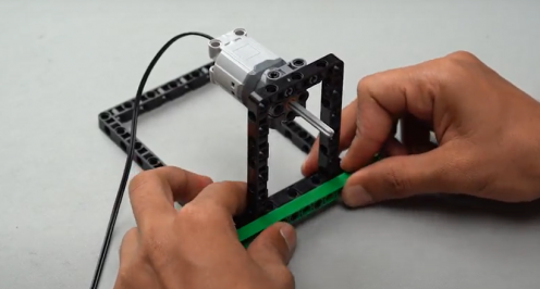 Now a Technic beam of size 15 is taken and is attached on the frame of our spin wheel robot with the help of frictionless Technic pegs. This creates the body of our spin wheel robot, a STEM robotic project.