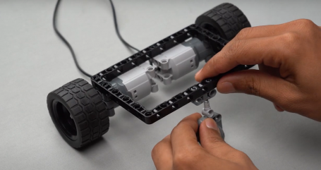 Connecting the caster wheel to the pin connector on the block using a block joiner, showcasing an easy robot project powered by Roboki, part of an innovative robotic and electronic project by Yudu Robotics, perfect for robotics enthusiasts exploring autonomous robot ideas and mobile robots.