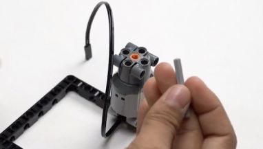 Once the setup is ready, carefully attach axle 5 to the motor, creating an extension for mounting the basket in this fun robotics activity focused on interactive play.