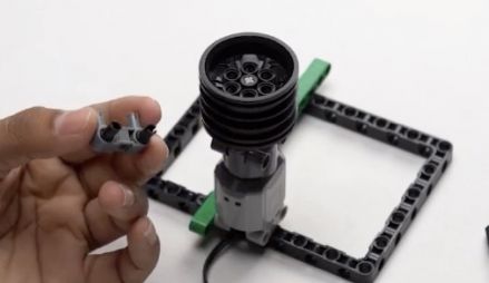 Take a pin connector and attach two pegs to it, preparing to secure the components of your Object Finder Robot. This step is important for the structural integrity of the mobile bot.