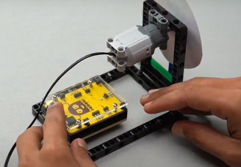 The Roboki microcontroller is connected on top of the 1 by 6 brick, integrating it into our spin wheel robot for enhanced functionality in this STEM robotics project.