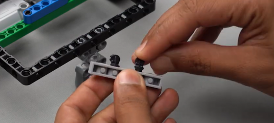 1 by 6 brick with holes connected to two 90-degree pegs, serving as a mount on Beam 5. This image illustrates the assembly of mobile robots with Roboki.