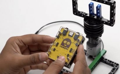 Connect the Roboki microcontroller on top of the 1 by 6 brick, integrating the brain of your Object Finder Robot. This connection is essential for programming AI recognition capabilities into the mobile bot.