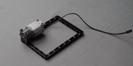 The motor connected to the block in the assembly of a line follower robot, showcasing the integration of motors in robotic engineering for effective sensor-based navigation.